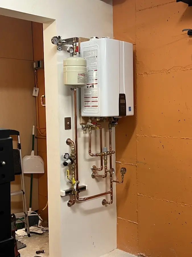 Plumbing technician inspecting water heater connections in Hector